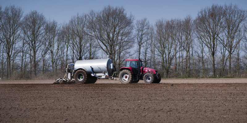a tractor with trailer spreads slurry on a field