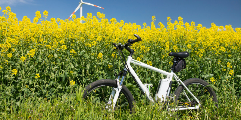 ein weißes Elektrorad steht vor einem Rapsfeld 