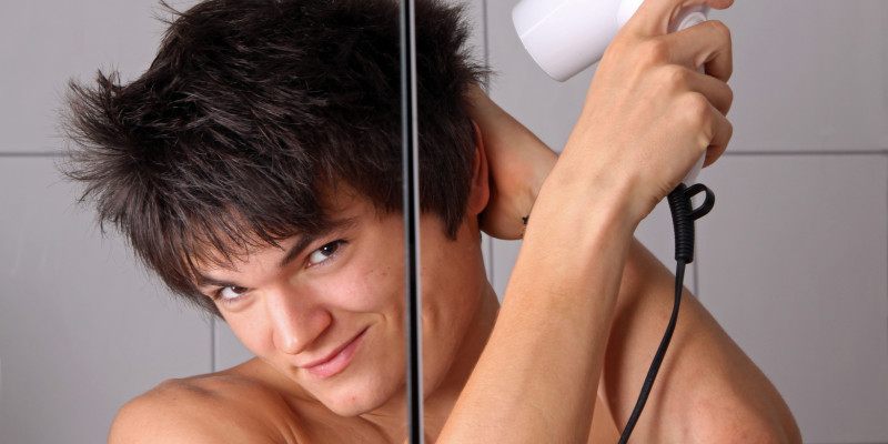 Junger Mann föhnt sich die Haare