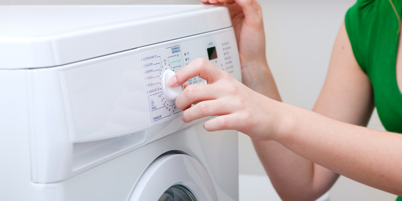 Eine Frau dreht am Programmwählknopf einer Waschmaschine.