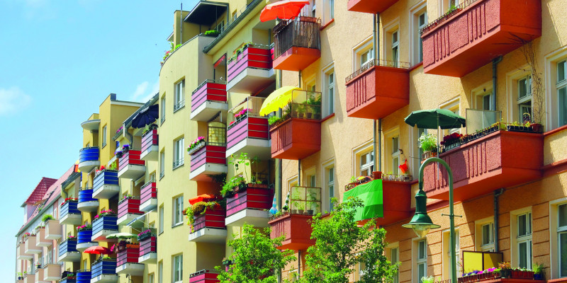 Blockrandbebauung: Mehrere Mehrfamilienhäuser, Neu- und Altbauten mit bepflanzten Balkonen,  Dachausbauten