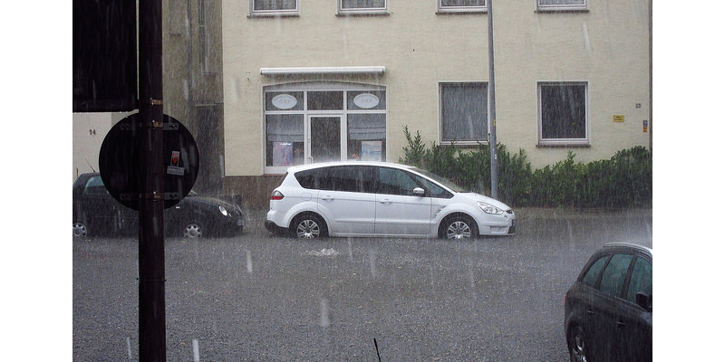 Eine überschwemmte Straße mit geparkten Autos