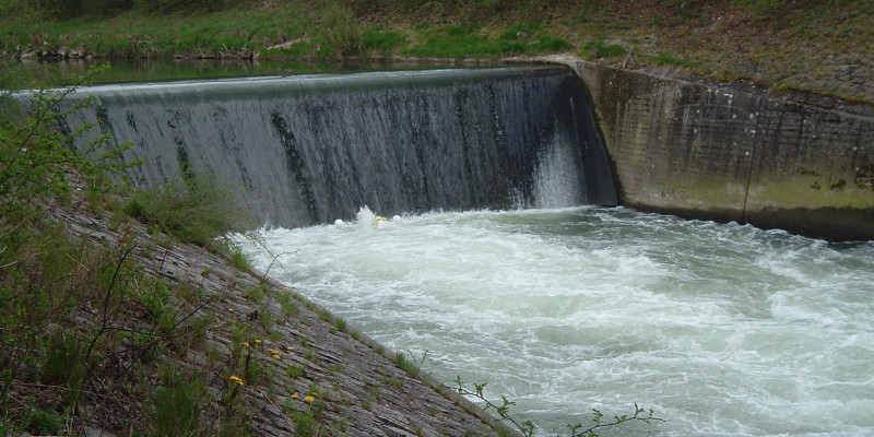Querbauwerk in einem Fluss - Wasser fließt senkrecht eine Wand herunter