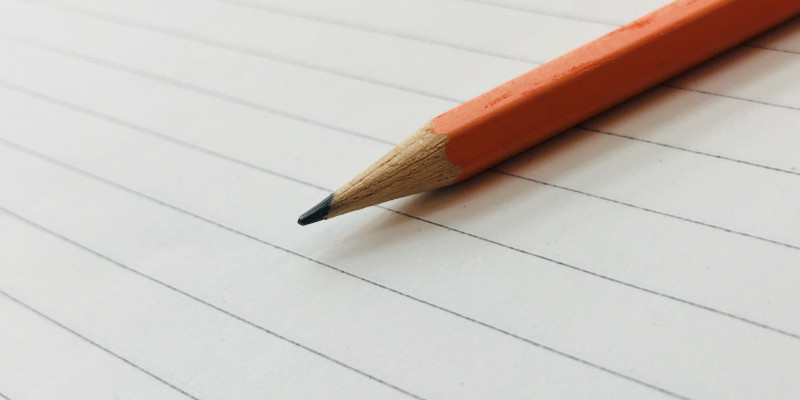 Ein Bleistift liegt auf einer linierten Seite Papier