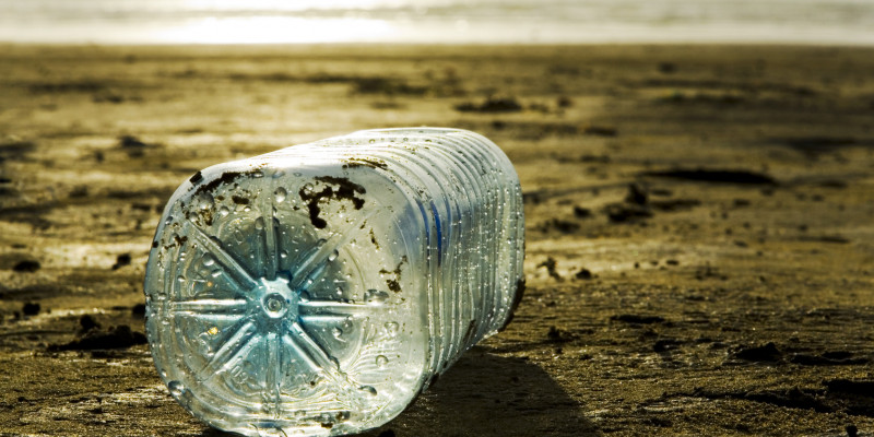 Eine Plastikflasche liegt am Strand.