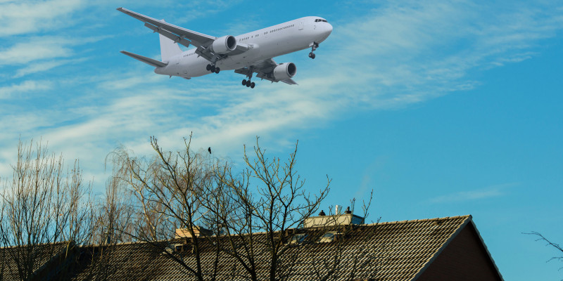 Ein Flugzeug fliegt über ein Wohngebiet.