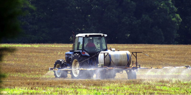 Ein Traktor sprüht Pflanzenschutzmittel auf ein Feld.