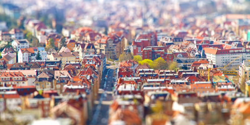 Eine Stadt aus der Luft, es sind Dächer und eine Straße zu sehen.