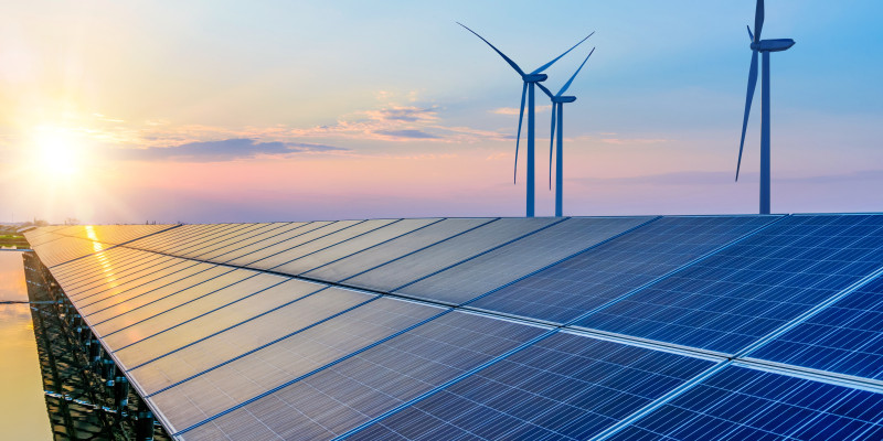The photo shows a solar park and several wind turbines