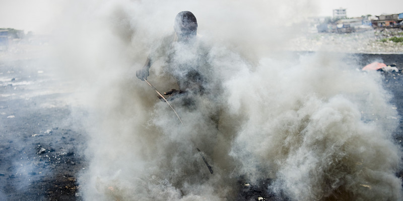 Mensch in Rauchschwaden bei der Verbrennung von Schrott.