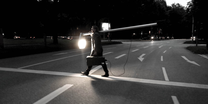 Mann mit leuchtender Laterne läuft über eine Straße.