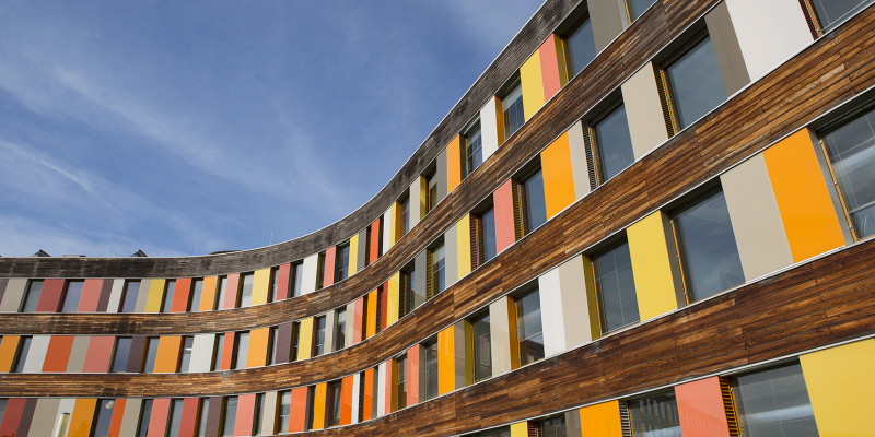 Rückwärtige Holz-Fassade des UBA Dessau-Roßlau mit Glasplatten in verschiedenen Rottönen