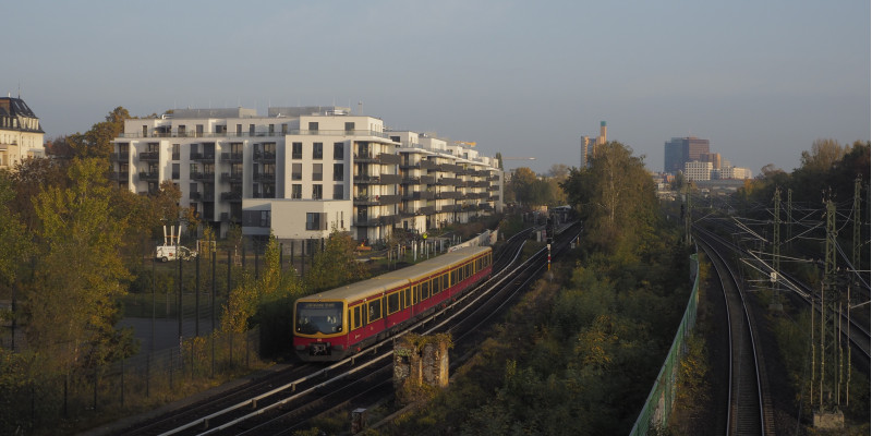 View on rails with a suburban train, behind it city panorama