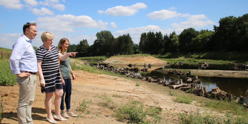 Das Bild zeigt Landrat Dr. Kai Zwicker gemeinsam mit Kordula Blickmann und Jessica Mach vom Fachbereich Natur und Umwelt bei einem Ortstermin in Borken-Hoxfeld. Es erfolgt die Begutachtung der umgesetzten Wasserrahmenrichtlinien-Maßnahme.