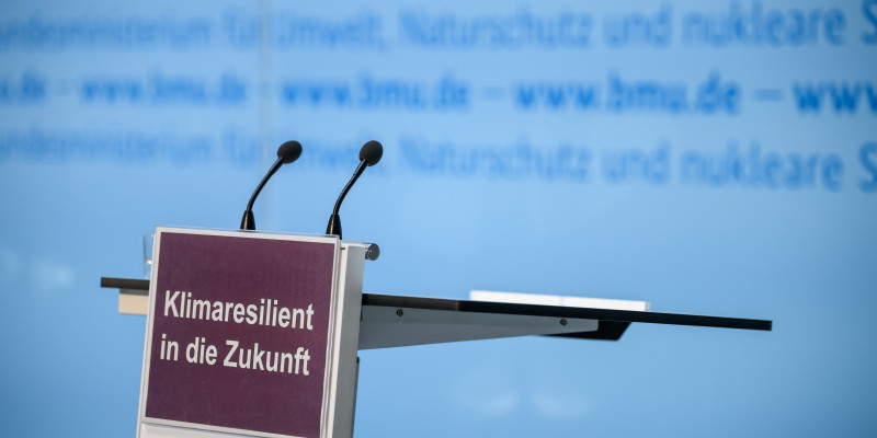 Ein leeres Sprechpodest mit zwei Mikros und einem Schild Klimaresilient in die Zukunft