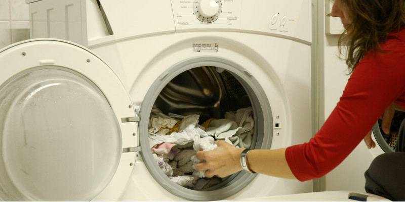 Frau entnimmt Wäsche aus der Waschmaschine.