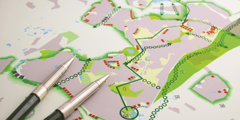 Das Bild zeigt einen Plan mit verschiedenen farbigen Plansymbolen und einen darauf liegenden Stift. 