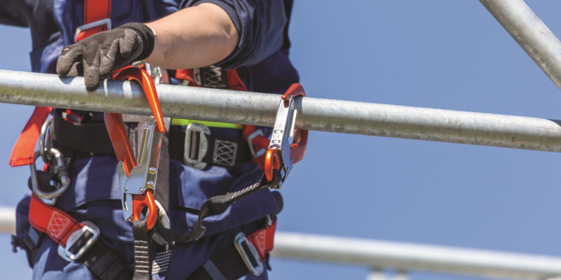 The picture shows a person in action with a climbing harness hooked into a metal frame.
