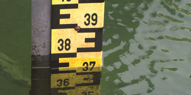 The picture shows a water level gauge in a calm body of water.