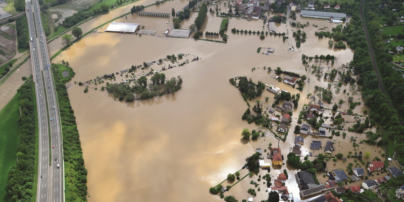The picture shows an aerial view of a landscape that has been flooded over a large area. The settlement areas are completely under water.