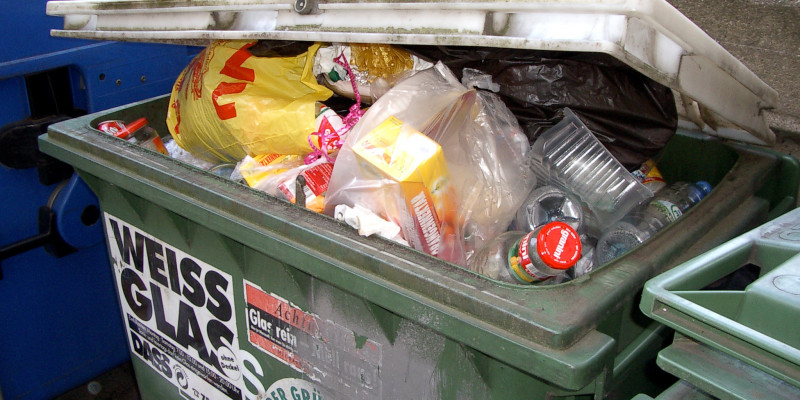 Glass container contains white glass bottles, but also plastic waste