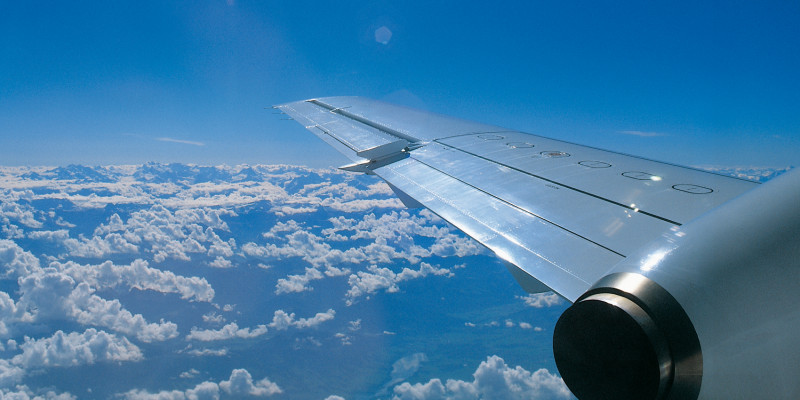 rechter Flugzeugflügel über den Wolken bei blauem Himmel