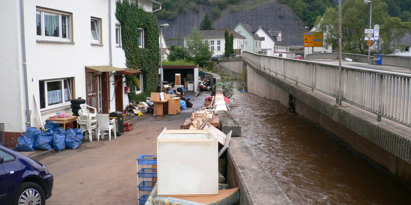 Durch die Sturzflut zerstörte Möbel stehen vor Wohnhäusern.