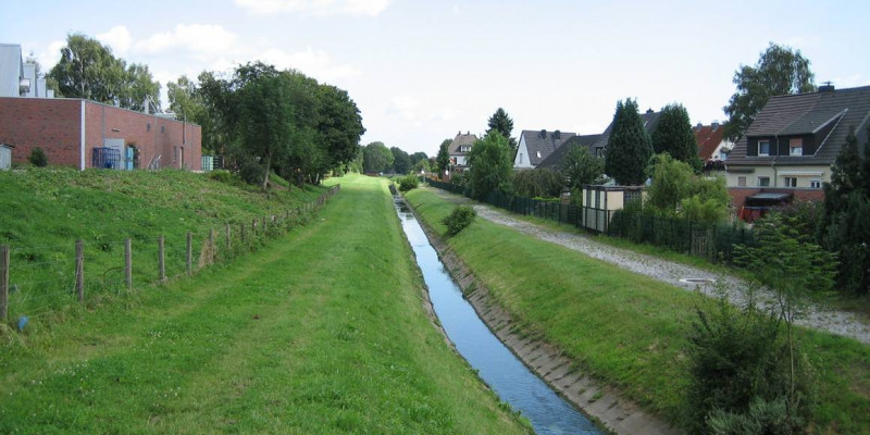 Ein Bach fließt im Grünen am Ortsrand entlang