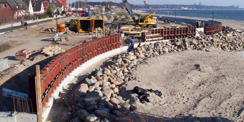 Menschen bauen einen Hochwasserschutz in Form eines Strandwalls, der sowohl an eine Siedlung als auch ans Meer grenzt