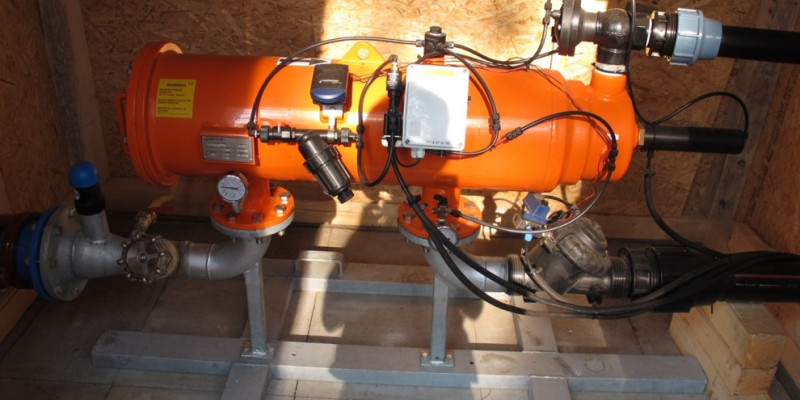 Auf dem Bild sieht man ein zylindrisches Gerät, welches den Feinfilter darstellt. Die Farbe ist orange. Verschiedene Zu- und Ableitungen sowie Messgeräte sind außen am Gerät zu sehen.