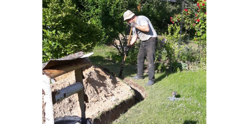 Ein Mann arbeitet am Grabenaushub für Erdwärme-Flachkollektor.