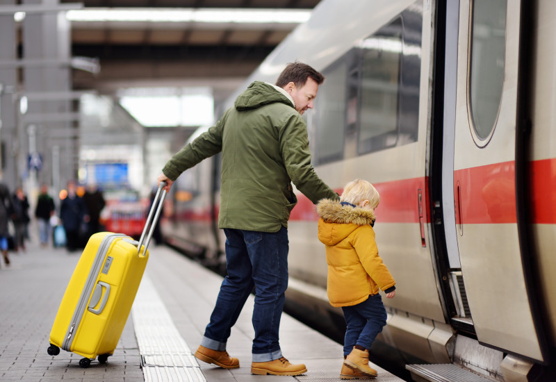 Mann und kleines Kind steigen in einen Zug ein.
