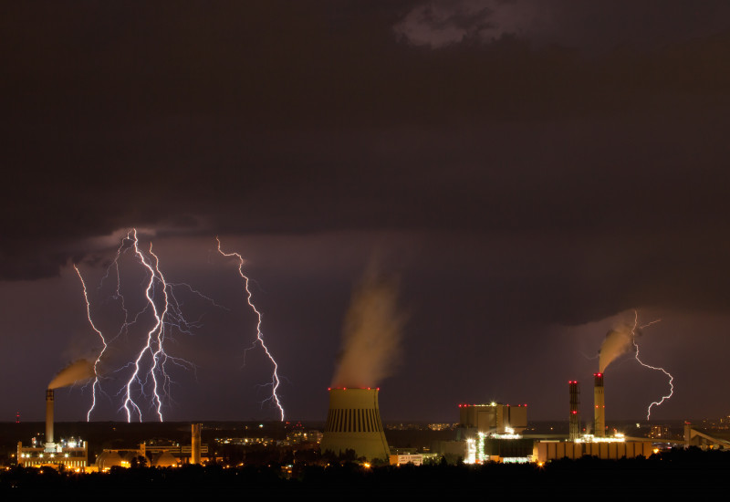 Das Bild zeigt Blitze über einer industriellen Anlage.