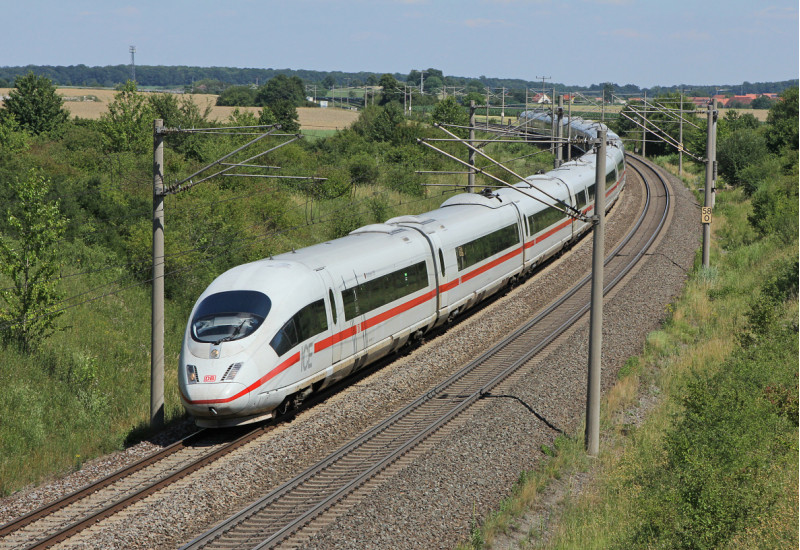 Das Bild zeigt einen fahrenden ICE 3 der Deutschen Bahn AG in ländlicher Umgebung.