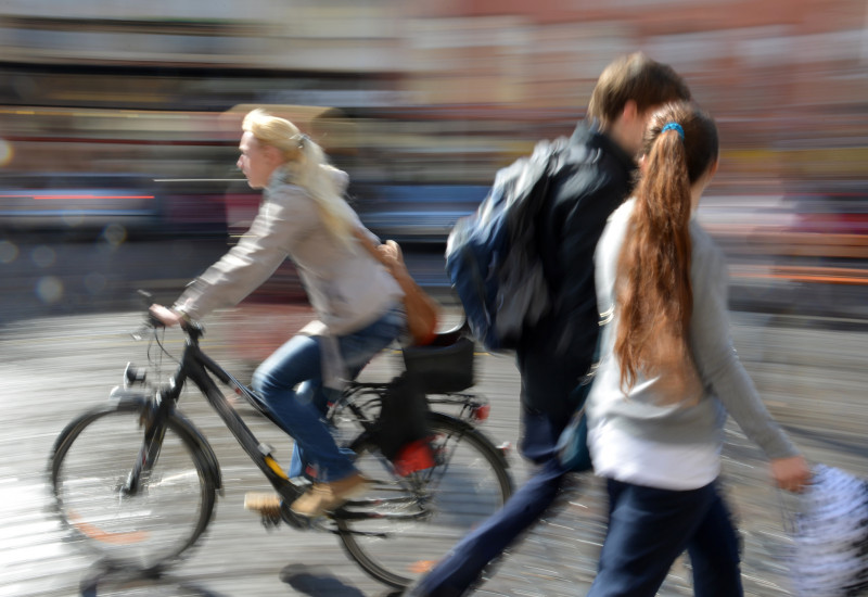 Fußgänger und Radfahrerin in einer Stadt.