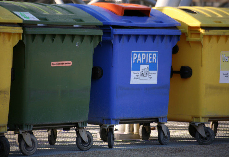 Müllcontainer in grün, blau und gelb für verschiedene Abfälle.
