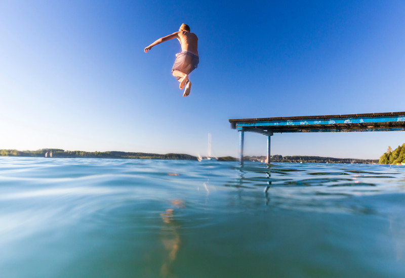 Junge springt vom Steg in einen See