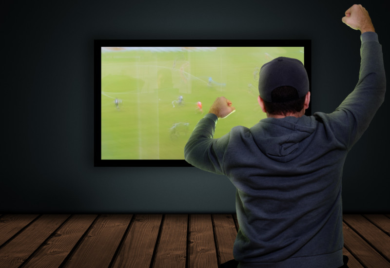 Mann schaut auf Flachbildfernseher ein Fußballspiel