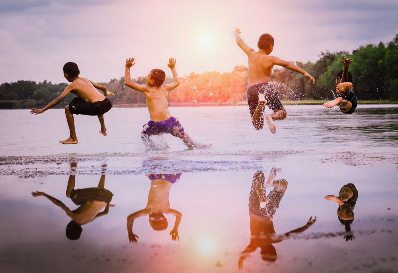 Vier Jungen springen in einen See.