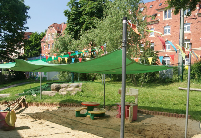 Das Bild zeigt einen Sandkasten über den ein Sonnensegel gespannt ist
