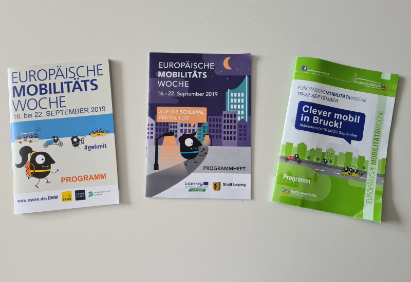 Drei Programmhefte der Europäischen Mobilitätswoche in unterschiedlichem Design aus Essen, Leipzig und Fürstenfeldbruck