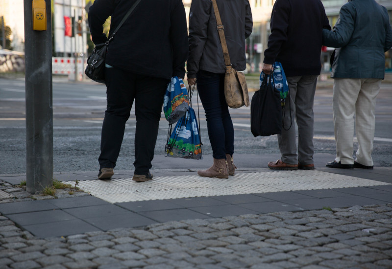 Fußgänger halten Frühstücksbeutel in der Hand, die sie eben erhalten haben. Auf den Beuteln ist das EMW-Design zu sehen. 