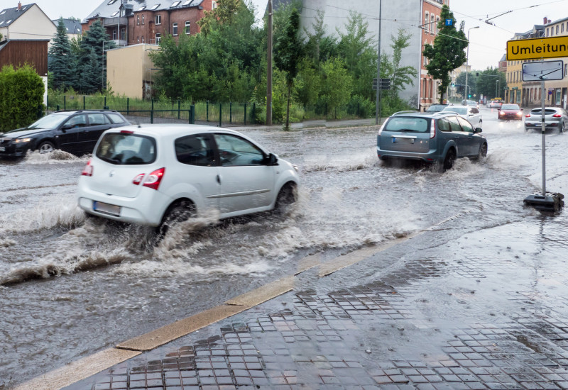 Auto fährt überflutete Straße entlang