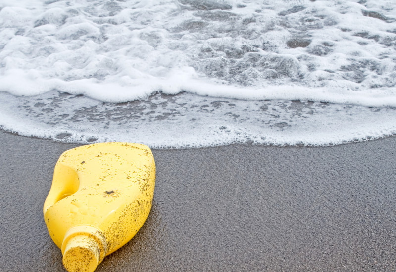 Gelbe Plastikflasche am Strand
