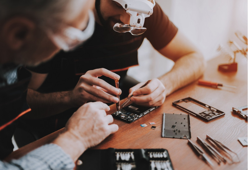 Zwei Männer haben ein Elektrogerät aufgeschraubt, um es zu reparieren