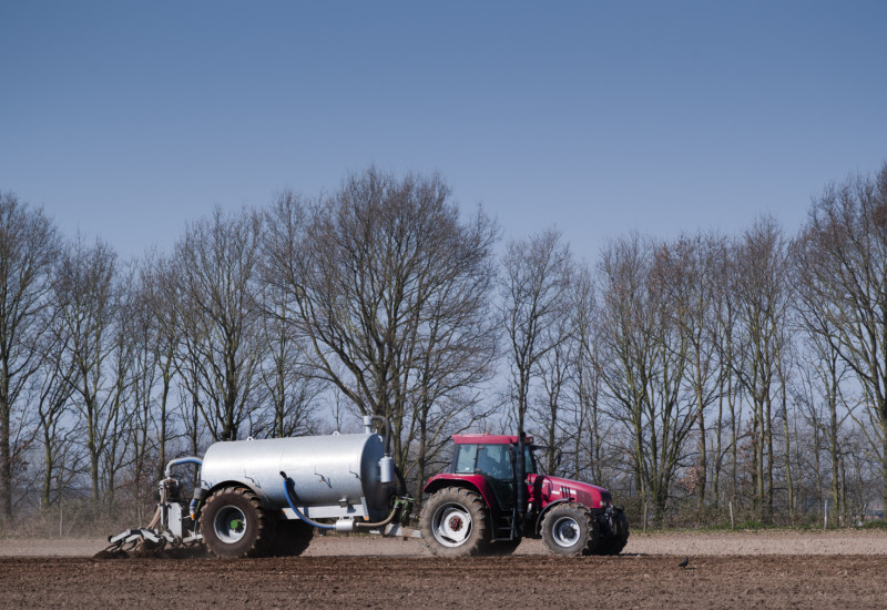 Großaufnahme eines Traktors, der auf einem Feld Gülle ausfährt