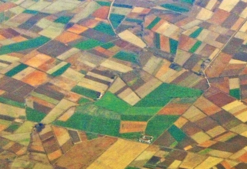 Bird's eye view of geometrical arranged, colourful fields and settlements