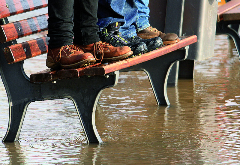 People standing on a seat bench surrounded by water