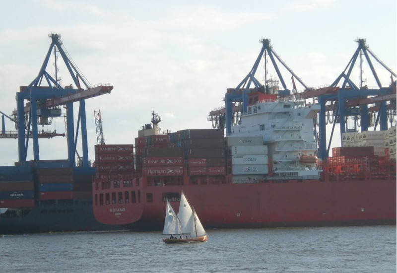 Sailing boat and container ship in the harbor of Hamburg