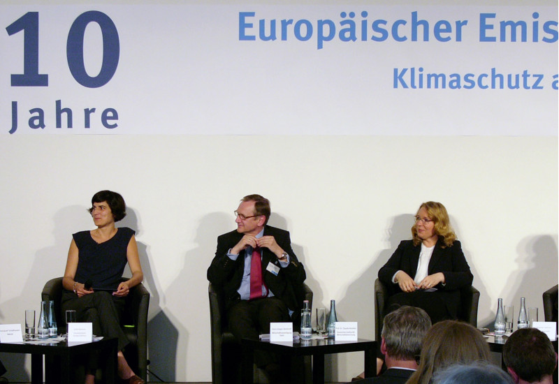 drei Frauen und zwei Männer sitzen auf einem Podium und diskutieren. Auf einem Banner darüber steht "10 Jahre Europäischer Emissionshandel"